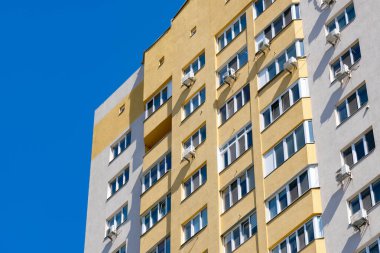 Mavi bir yay gökyüzünün arka planına karşı çok katlı, çok katlı bir apartmanın parçası, emlak objesi