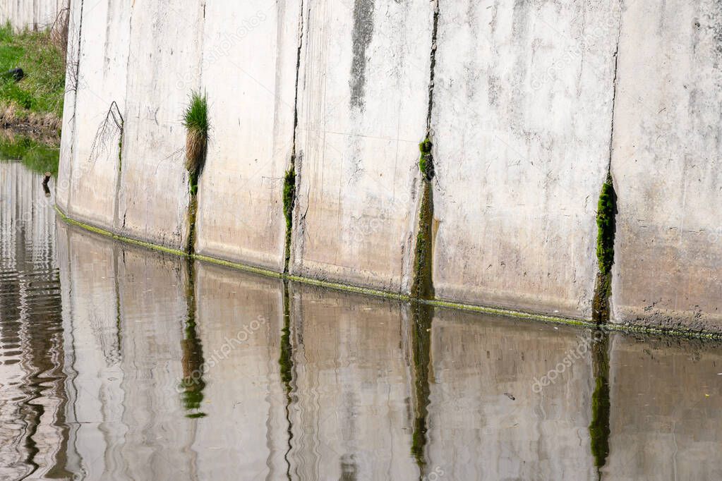 Concrete fortification of the shore of a reservoir on a bright spring day with reflection in the water