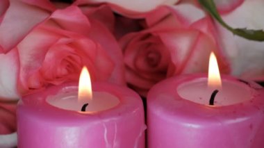 Video klibi iki kırmızı parafin mum yakın plan güllerin yanında yanıyor.