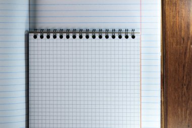 Cetvelinde beyaz çarşaflar ve kahverengi ahşap arka planda bir kutu olan boş defterler açılmış.