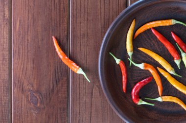 Evde ızgara kırmızı ve sarı biber ocağın üstünde, kahverengi kil tabakta, ahşap arka planda yakın plan.