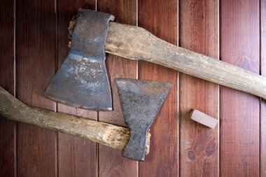 Koyu kahverengi ahşap arka planda paslı kör baltalar.