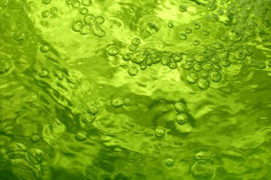 Kaynayan temiz suyun çok kısa pozlama kullanarak yeşil bir kabın içine akışını gösteren soyut bir fotoğraf.