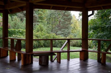 Huzurlu bir ahşap çardak, canlı sonbahar yaprakları arasında huzurlu bir geri çekilme sunar..