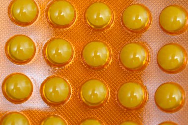 Canlı sarı kapsüller göz alıcı turuncu bir arka plana güzelce yerleştirilir..