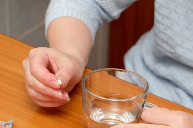 Tahta bir masada bir bardak suyla küçük bir tablet hazırlar..