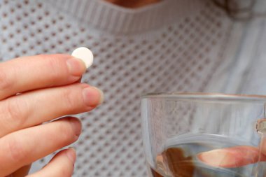 Bir el, buharı tüten bir çay bardağının içine bir tablet bırakmaya hazırlanır ve beklenti yaratır..