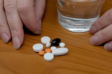 Eller çeşitli hapların yanına konur ve tahta bir yüzeye bir bardak su konur..