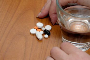 Birisi yakınlarda bir bardak suyla çeşitli haplar almaya hazırlanıyor..