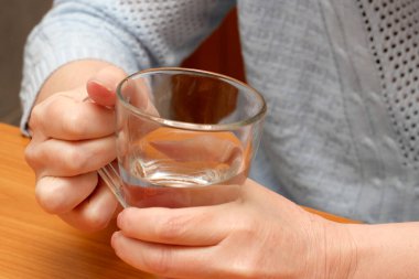 Bir insan elinde suyla dolu temiz bir bardak tutar, sessiz bir anın tadını çıkarır..