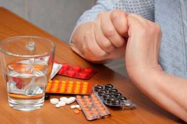 Birbirlerine kenetlenmiş eller, çeşitli ilaçlar ve su yakınlarda dinlenirken endişe gösteriyor..