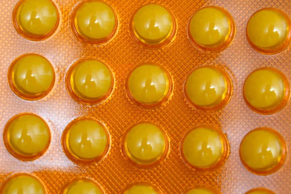 Canlı sarı kapsüller göz alıcı turuncu bir arka plana güzelce yerleştirilir..