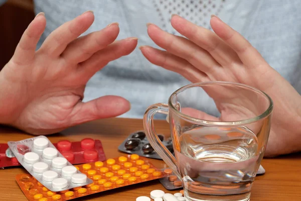 Eller çeşitli ilaç paketlerinin üzerine yerleştirildi ve bir bardak su kullanıma hazır..