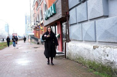 Kyiv 'de bir kadın, gri sonbahar manzarasına hayran kalarak kaldırımda yürüyor..