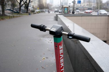 Sonbahar yaprakları düşerken sakin bir Kyiv caddesinde hareketli bir elektrikli scooter hazır bekliyor..