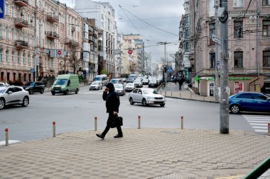 Etrafta araçlar ve binalar olan hareketli bir kavşakta bir kişi yürüyor. 24 Kasım 2025 Kyiv, Ukrayna