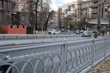 Bulutlu bir günde, tarihi binalarla dolu ıslak bir caddede arabalar gezinir. 24 Kasım 2025 Kyiv, Ukrayna