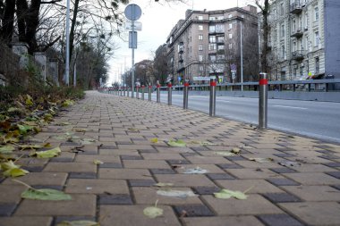 Sakin bir şehir kaldırımı, patika boyunca düşen yaprakları ve korkulukları gösteriyor. 24 Kasım 2025 Kyiv, Ukrayna