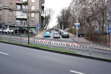 İnsanlar kaldırımda yürürken arabalar yol boyunca park halindedir. 24 Kasım 2025 Kyiv, Ukrayna