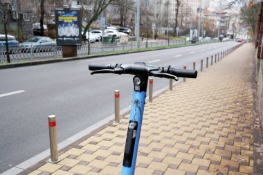 Parlak mavi bir scooter kışın sakin bir şehir caddesinde bir sonraki yolculuğunu bekliyor. 24 Kasım 2025 Kyiv, Ukrayna