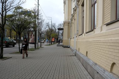 Bir insan bulutlu gökyüzü ile sakin bir şehir ortamında tuğla kaldırım boyunca yürür. 24 Kasım 2025, Kyiv, Ukrayna, Shevchenko Bulvarı