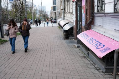 İki kadın şehir kaldırımında bir bar tabelasının yanında yan yana yürüyor. 24 Kasım 2025, Kyiv, Ukrayna, Shevchenko Bulvarı