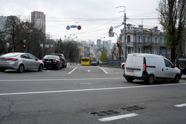 Arabalar bulutlu bir gökyüzü altında hareketli bir şehir kavşağında yol alırlar. 24 Kasım 2025, Kyiv, Ukrayna, Shevchenko Bulvarı