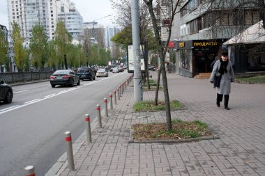 Modern binalar ve arabalarla çevrili bir kadın şehir kaldırımında yürüyor. 24 Kasım 2025, Kyiv, Ukrayna, Shevchenko Bulvarı