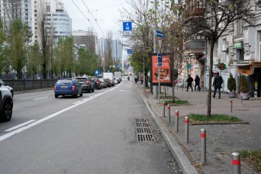 İnsanlar canlı bir kentsel alanda ağaçların yanında yürürken arabalar yol boyunca diziliyorlar. 24 Kasım 2025, Kyiv, Ukrayna, Shevchenko Bulvarı