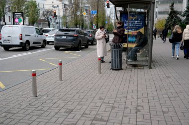 Diğerleri kalabalık bir şehir caddesinde yürürken iki kadın otobüs durağında duruyor. 24 Kasım 2025, Kyiv, Ukrayna, Shevchenko Bulvarı