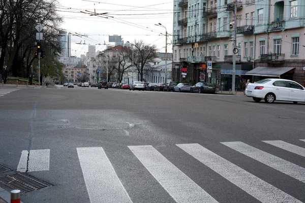 Gri bir öğleden sonra park halindeki arabaların ve boş kaldırımların kesiştiği sakin bir şehir kavşağı. 24 Kasım 2025 Kyiv, Ukrayna