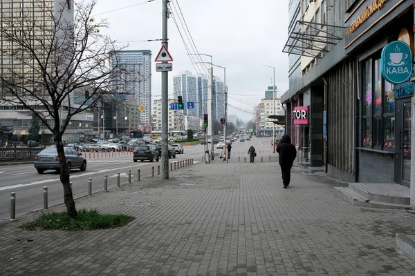 Şehir ortamında bulutlu bir gökyüzünün altında hareketli bir caddede gezinen bir insan. 24 Kasım 2025, Kyiv, Ukrayna, Shevchenko Bulvarı