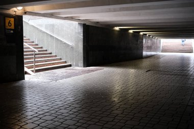 Sakin bir yeraltı geçidi, parlak gün ışığına doğru yükselen merdivenler içerir..