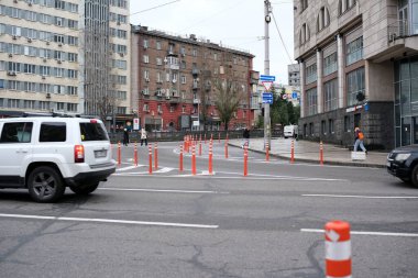 Arabalar sonbaharda işlek bir şehir caddesinde parlak turuncu bariyerler etrafında yol alırlar. Kyiv, Ukrayna, 26 Kasım 2025.