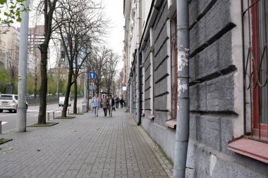 İnsanlar ağaçlar ve binalarla dolu huzurlu bir şehir kaldırımında yürüyor. Kyiv, Ukrayna, 26 Kasım 2025.