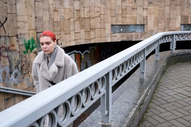 Genç bir kadın şehir yolunda tek başına yürüyor, çarpıcı kızıl saçları öne çıkıyor. Kyiv, Ukrayna, 26 Kasım 2025.