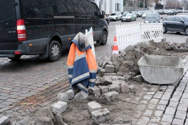 Bir işçi ceketi kaldırım taşı yolda inşaat açılırken bir bariyere asılıyor. Kyiv, Ukrayna, 26 Kasım 2025.