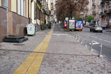 Canlı bir şehir manzarası, kendine özgü bir yolu olan iyi korunmuş bir kaldırımı gösteriyor. Kyiv, Ukrayna. 26 Kasım 2025.