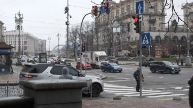 Araçlar ve insanlar bulutlu gökyüzünün altında hareketli bir cadde boyunca ilerliyorlar. Khreshhatyk, Kyiv, Ukrayna. 26 Kasım 2025.