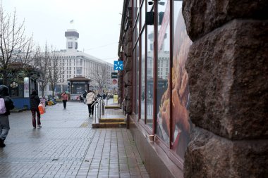 İnsanlar kasvetli bir günde dükkanlarla dolu hareketli bir cadde boyunca yürürler. Khreshhatyk, Kyiv, Ukrayna. 26 Kasım 2025.