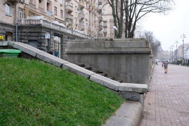 Dolambaçlı bir yol, çimenli alanları işlek bir şehirde katı bir taş yapıya bağlar. Khreshhatyk, Kyiv, Ukrayna. 26 Kasım 2025.