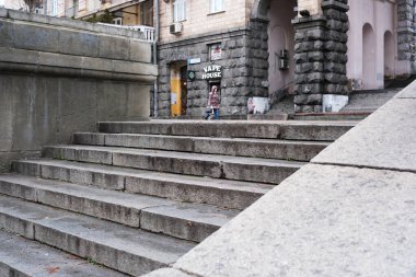 Bir çocuk, sakin bir alandaki tuhaf bir yapıya doğru, taş basamaklara doğru yürür. Khreshhatyk, Kyiv, Ukrayna. 26 Kasım 2025.