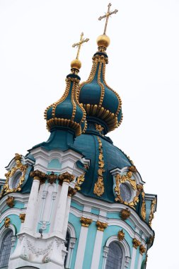 Altın kubbeler güzel bir şekilde gri gökyüzüne doğru yükselirler, karmaşık detaylar sergilerler..