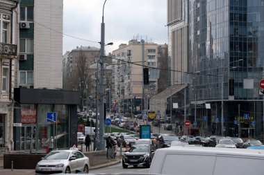 Arabalar ve insanlar bulutlu bir günde canlı bir şehir merkezinde akarlar. Kyiv, Ukrayna. 12 Aralık 2025.