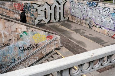 Bir insan renkli grafiti sanatıyla süslenmiş canlı bir sokakta yürüyor. Shevchenko Bulvarı. Kyiv, Ukrayna. 16 Aralık 2025.