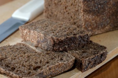 Taze pişmiş ekmek, dilimlenmiş ve tadını çıkarmaya hazır ahşap bir yüzeyde oturur..