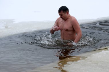 Cesur bir birey, buz ve karla çevrili dondurucu sulara dalıyor. Kyiv, Ukrayna, 6 Ocak 2026. Epifani 'de buz deliği banyosu.