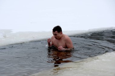 Buz gibi sularda, karlı oluşumlarda yüzen bir adam. Kyiv, Ukrayna, 6 Ocak 2026. Epifani 'de buz deliği banyosu.