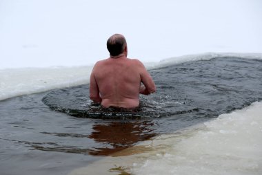 Cesur bir yüzücü kendini karla çevrili soğuk sulara batırır. Kyiv, Ukrayna, 6 Ocak 2026. Epifani 'de buz deliği banyosu.