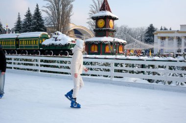 Karla kaplı ağaçlar ve şenlikli dekorlarla çevrili bir patenci buzun üzerinde süzülüyor. Kyiv, Ukrayna, Ukrayna Expocenter 'ı. 14 Ocak 2026.